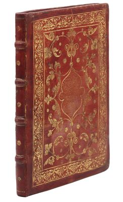 un vieux livre à la couverture rouge ornée de motifs dorés