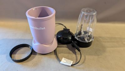 un mixeur rose posé sur une table à côté d'une tasse