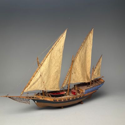 a model of a boat with sails on a gray surface