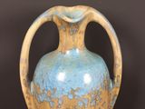 a blue and yellow vase sitting on a wooden table