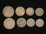 six different types of silver coins on a black surface