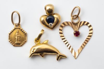 three gold charms including a dolphin, a heart, and a medal