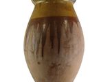 un vase brun posé sur une surface blanche