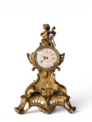 a gold clock on a stand on a white surface