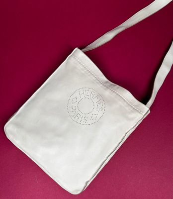 white canvas bag with a cross on it on a red surface