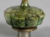 a close up of a green vase on a white surface
