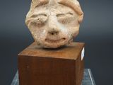 un gros plan d'une sculpture représentant un visage sur un bloc de bois
