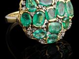 un gros plan d'une bague sertie d'émeraudes et de diamants sur un fond noir