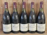 six bottles of wine are lined up on a shelf in front of a wooden wall