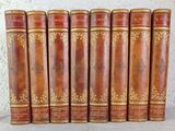 six antique leather books lined up on a shelf