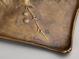 a gold plate with a bird on it on a table