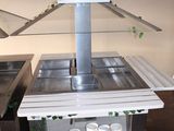a small kitchen with a stove, sink, and potted plants on the wall