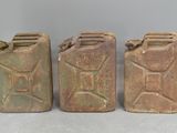 three old jerry canisters are lined up on a table