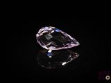 a close up of a pink diamond on a black surface