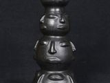 black ceramic sculpture of three faces on top of each other