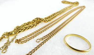 three different types of gold chains and a ring on a white surface