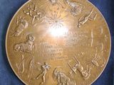 a gold plate with a picture of people and animals on it
