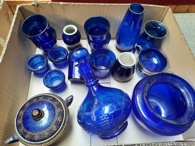 de nombreux objets en verre bleu dans une boîte posée par terre