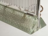 a glass case with a metal handle on a white surface