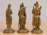 three brass figurines of hindu deities on a wooden table