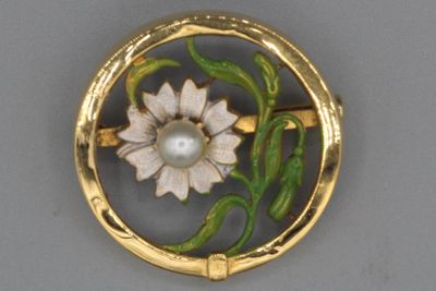 une image représentant une broche ornée d'une fleur et d'une perle au centre