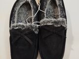 une paire de pantoufles noires doublées de fourrure, posées sur un fond blanc