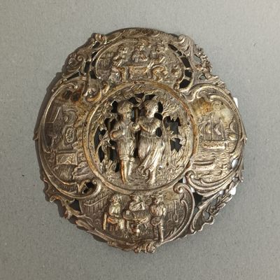 une broche ancienne en argent sur laquelle est représenté un homme et une femme