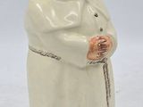 une figurine représentant un homme vêtu d'une robe blanche et tenant une canne