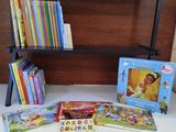 de nombreux livres pour enfants posés sur une table, avec une bibliothèque en arrière-plan