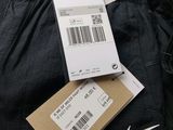 two pairs of black pants with a price tag and a pair of white shoes