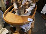 a doll sitting in a high chair with a doll in it