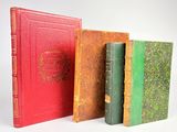 trois vieux livres sont alignés sur une surface blanche