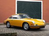yellow porsche 911 parked in front of a building with a green garage door