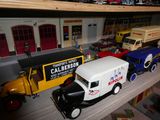 Plusieurs camions miniatures sont alignés sur une étagère dans une pièce