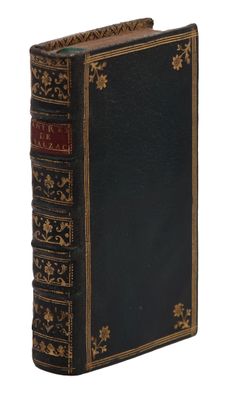 un vieux livre à la couverture noire, avec des bordures dorées sur fond blanc