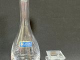 a glass bottle and a small glass candle holder on a table
