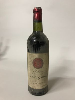 une vieille bouteille de vin posée sur une table blanche