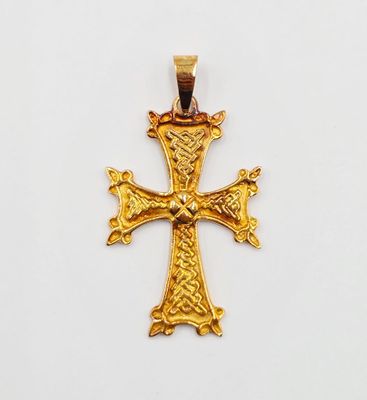 pendentif en forme de croix dorée sur fond blanc, avec un fond blanc