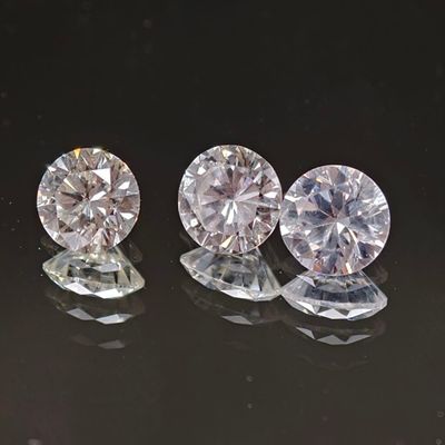 trois diamants ronds taille brillant sur une surface réfléchissante