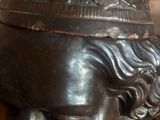 une statue d'un homme tenant un crayon et une plante en pot