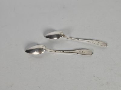deux cuillères en argent posées l'une à côté de l'autre sur une surface blanche