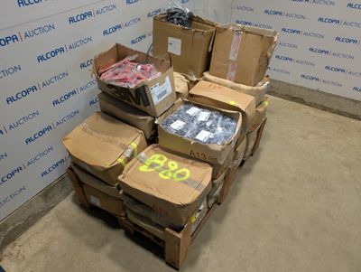 Des cartons contenant des articles variés sont empilés sur une palette devant un mur.