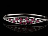 un gros plan d'une bague sertie de diamants et de rubis posée sur une surface noire