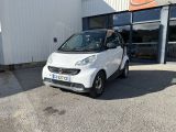 La Smart est garée devant un immeuble, sur un parking.