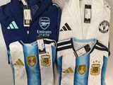trois maillots de foot sont posés côte à côte sur une étagère