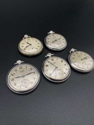 quatre montres de poche en argent posées les unes à côté des autres sur une table