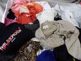 a white box filled with clothes and clothes on a bed