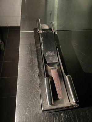 un plan de travail en acier inoxydable sur lequel est posé un couteau, dans une cuisine professionnelle