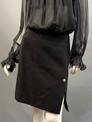 a mannequin wearing a black skirt and blouse with ruffled sleeves