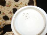 a person holding a cup and saucer with a plate in the background